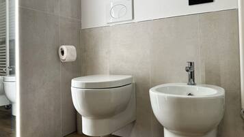 A modern bathroom with a toilet, bidet, and sink.