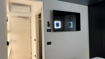 Ein modernes Hotelzimmer mit Holztür, einem angebrachten Fernseher und einem Kleiderschrank.