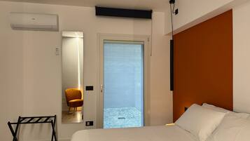 A modern bedroom with a bed, a chair, a black metal rack, and a door leading to a balcony.