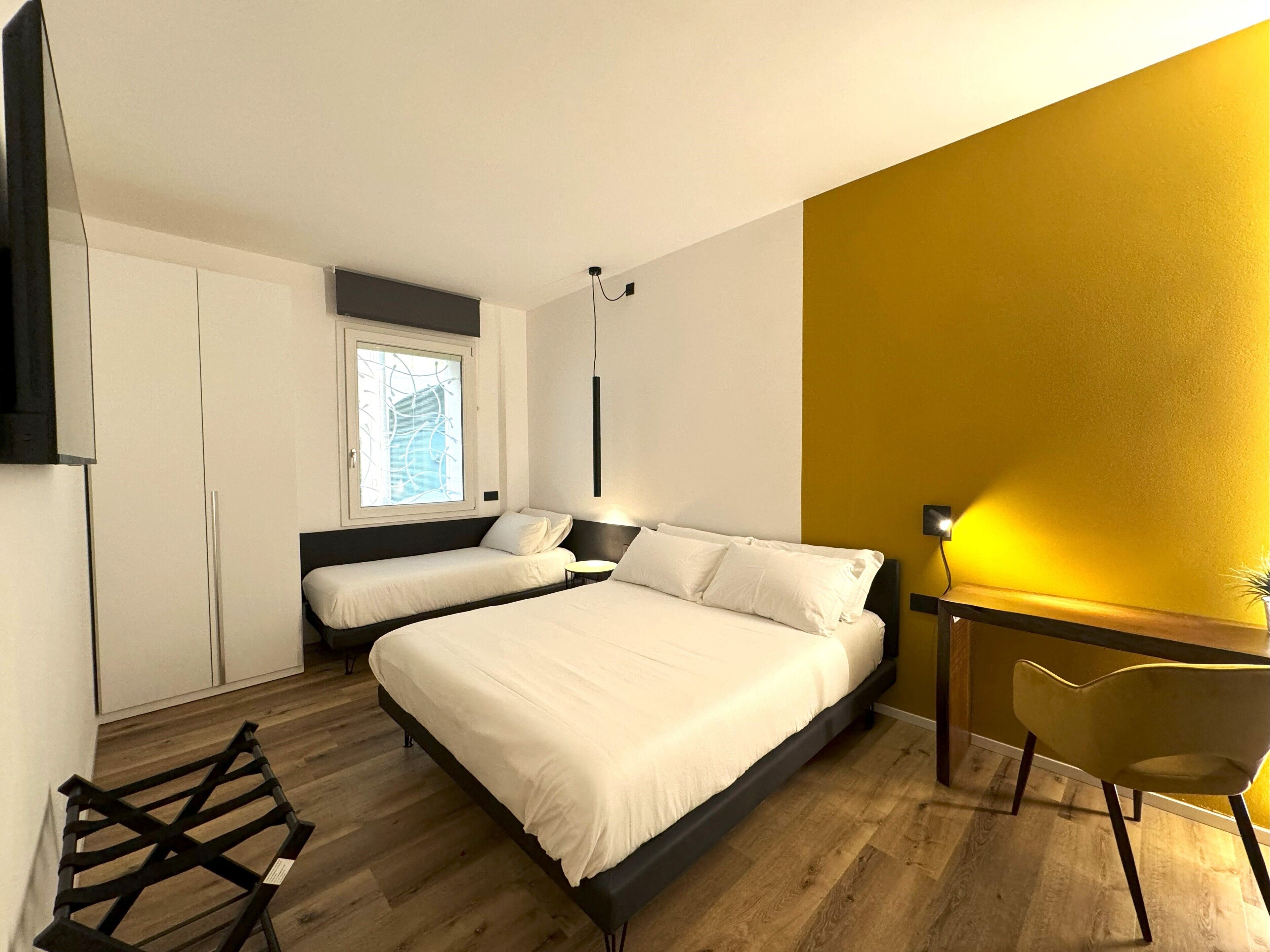 A modern bedroom with two beds, a desk, and a chair.