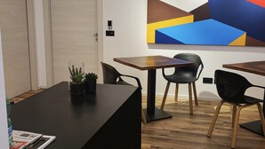 Ein moderner Büroraum mit zwei Holztüren, einem großen abstrakten Gemälde und einem Tisch mit Stühlen.