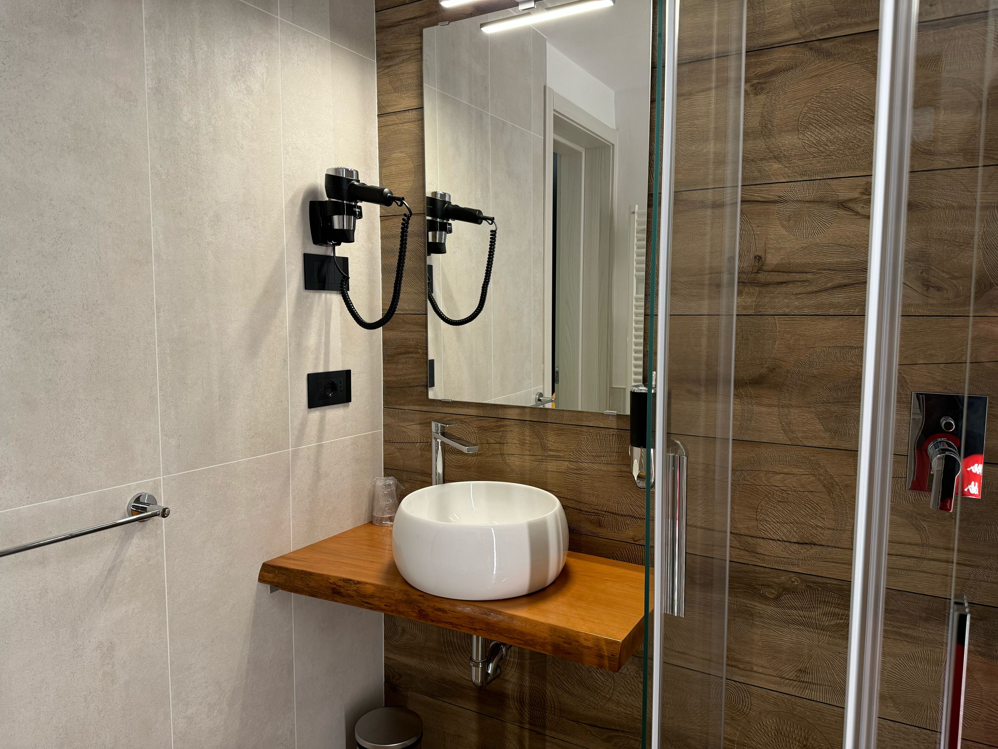 Une salle de bain moderne avec un meuble-lavabo en bois, un lavabo blanc et un miroir.