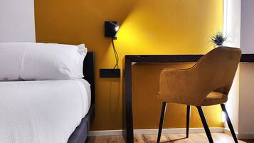 Una habitación de hotel con cama, escritorio y una silla.
