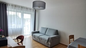 Una sala de estar moderna con un sofá gris, una mesa de comedor de madera y una lámpara de techo.