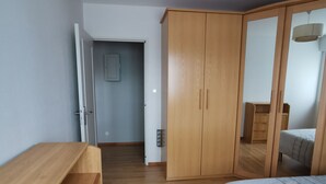 Un dormitorio con un armario de madera, una cama y un escritorio.