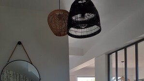 Ein geräumiger Wohnbereich mit einer weißen Treppe, einem großen Spiegel und zwei hängenden Korbstühlen.
