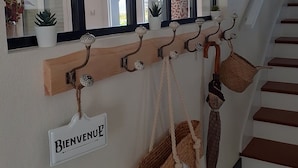 Eine Treppe mit Holzhandlauf, einem Willkommensschild und einem an der Wand befestigten Regal mit Taschen und einem Korb.