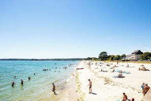 A beach with people swimming and sunbathing, a building with a sloped roof, and a clear sky. - Eugénie House 2/6 People Close to the Beaches, Private Garden, Private Parking (Concarneau)