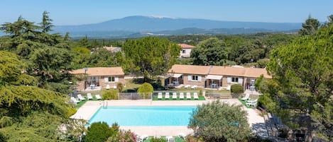 Una villa con piscina rodeada de exuberante vegetación y vistas a la montaña.