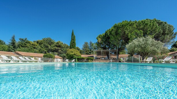 A clear blue pool with white lounge chairs and a covered seating area. - Cottage with AC and terrace n°10 (La Roque-sur-Pernes)