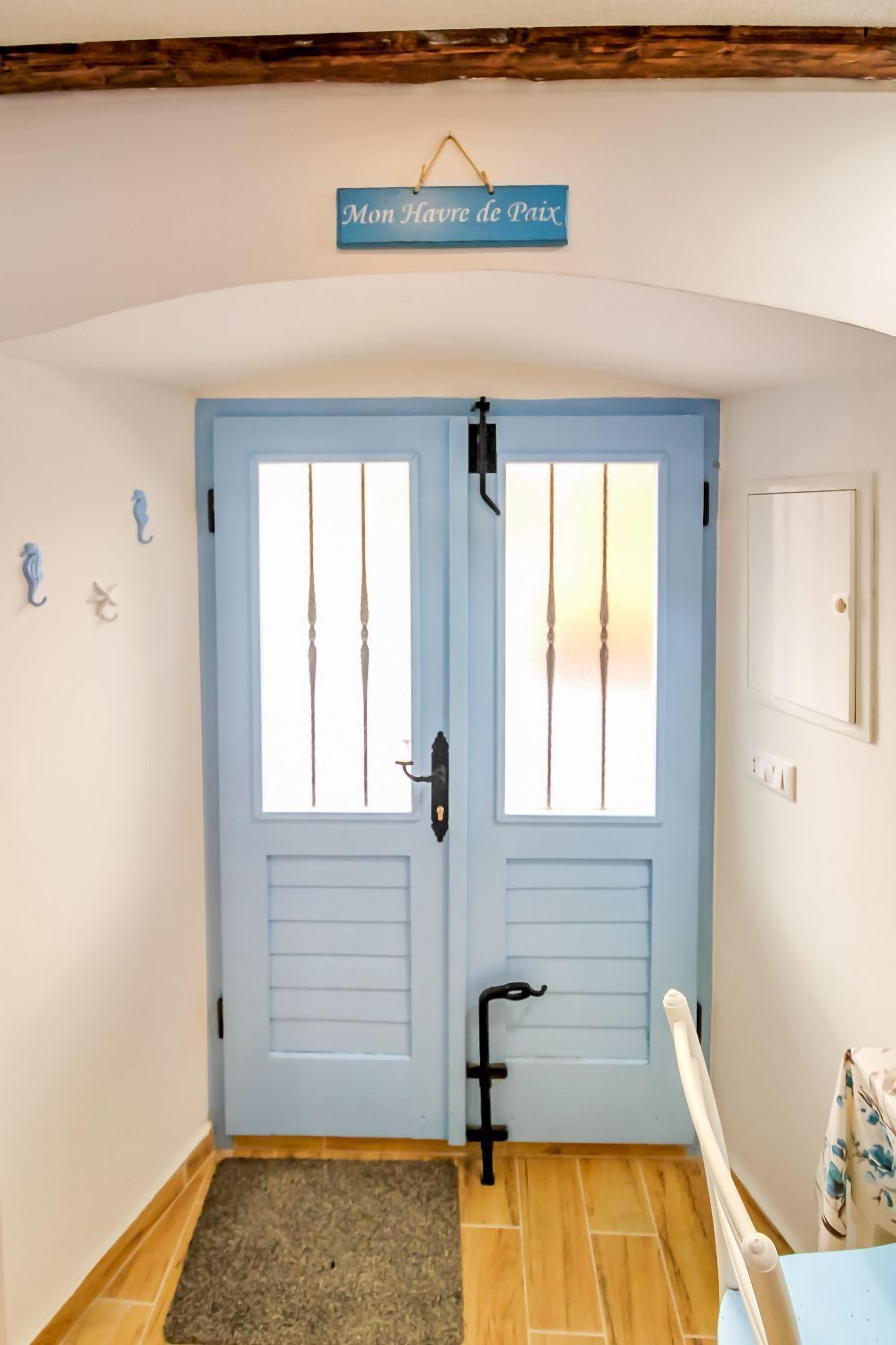 A hallway with a blue door, a small rug, and a sign above the door.