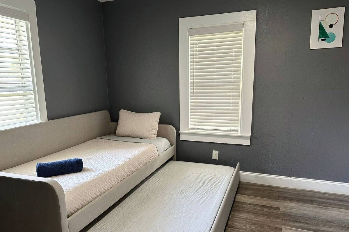 A compact room with a bed, a window, and a wall-mounted artwork.