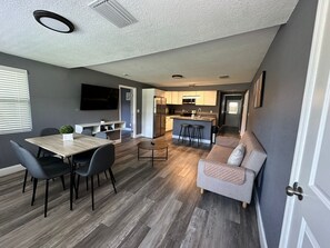 A modern living space with a dining area, kitchen, and seating area. - Gran casa para 8 cerca de Atraciones (Tampa)