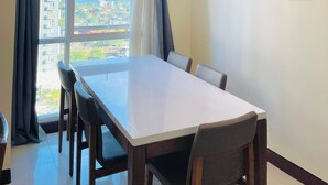 Un espace de salle à manger moderne, doté d’une grande table et de chaises, offrant une vue sur la mer et éclairé par un luminaire au plafond.