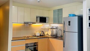 Une cuisine moderne avec des meubles blancs, des appareils en acier inoxydable et une poubelle noire.
