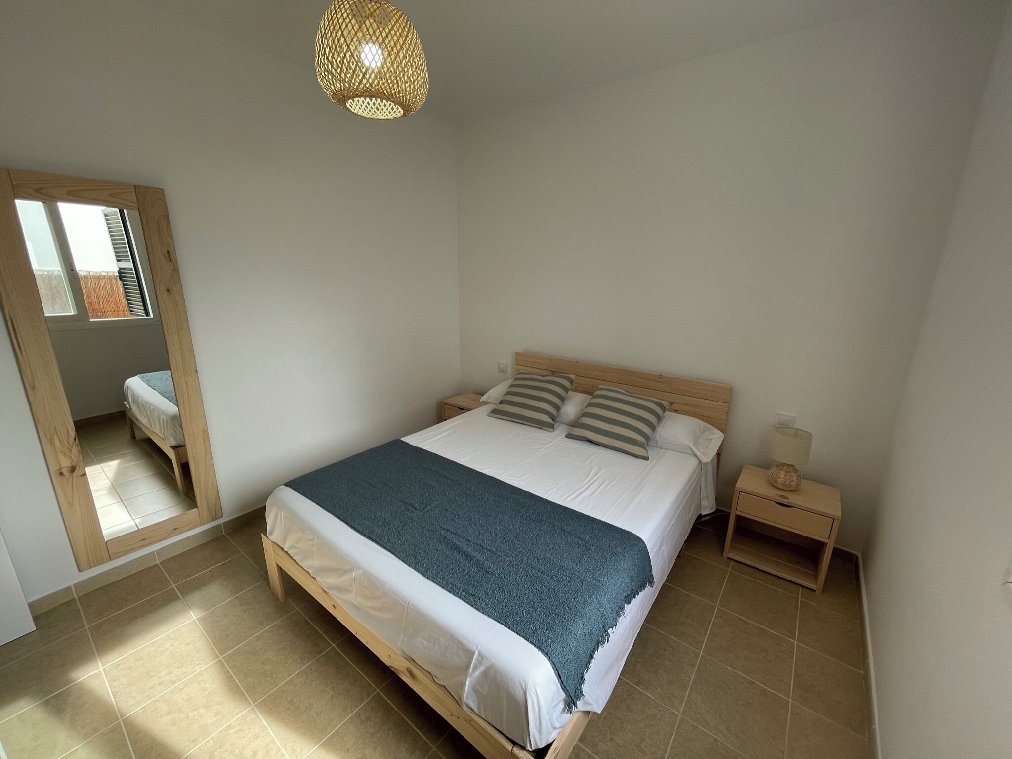 Ein Schlafzimmer mit einem hölzernen Bett, einem Nachttisch, einer Lampe und einer Pendelleuchte.