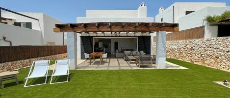 Eine moderne Außenpatio mit Pergola, einem Essbereich und einer Sitzecke.