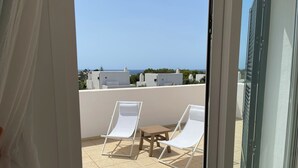 A balcony with two white lounge chairs and a small table, overlooking a coastal view. - Villa Can Simo Menorca (Sant Lluis)