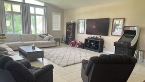 Un salon comprenant un canapé, des fauteuils, une table basse, un téléviseur, une bibliothèque et une petite table sur laquelle se trouve une voiture jouet.