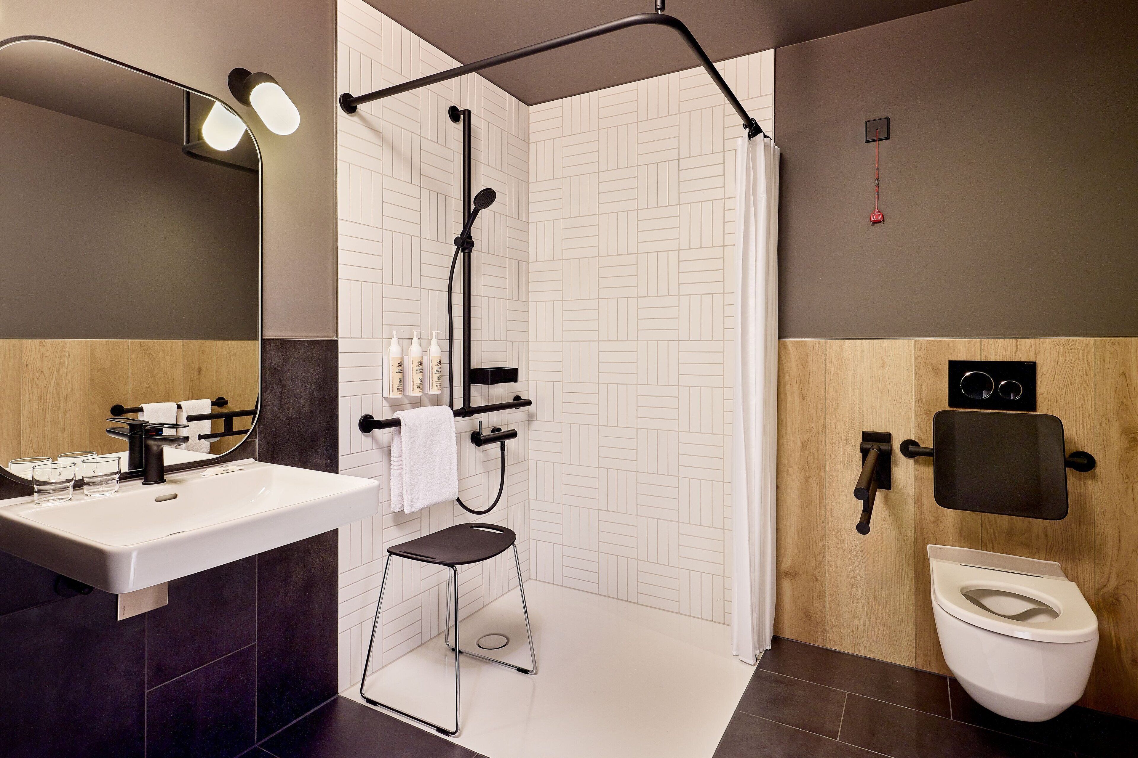 A modern bathroom with a sink, mirror, shower, and toilet.