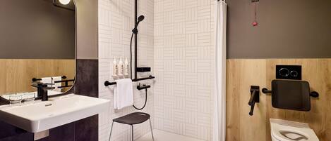 Un baño moderno con lavamanos, espejo, ducha e inodoro.