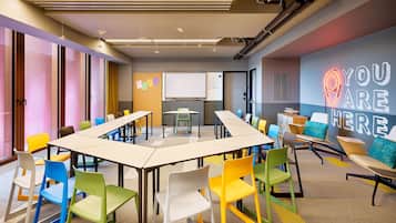 A modern meeting room with colorful chairs, a long table, and a motivational wall sign.