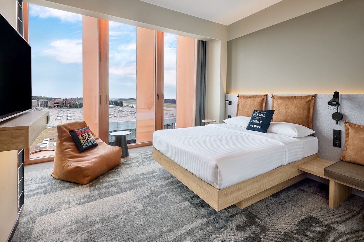 A hotel room with a large bed, a seating area, and a view of the cityscape.