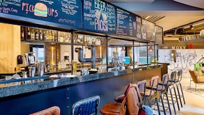Een bar met een krijtbordmenu, barstoelen en diverse flessen.