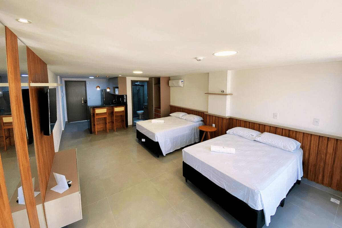 Ein Hotelzimmer mit zwei Betten, einem Schreibtisch und einer Dusche.