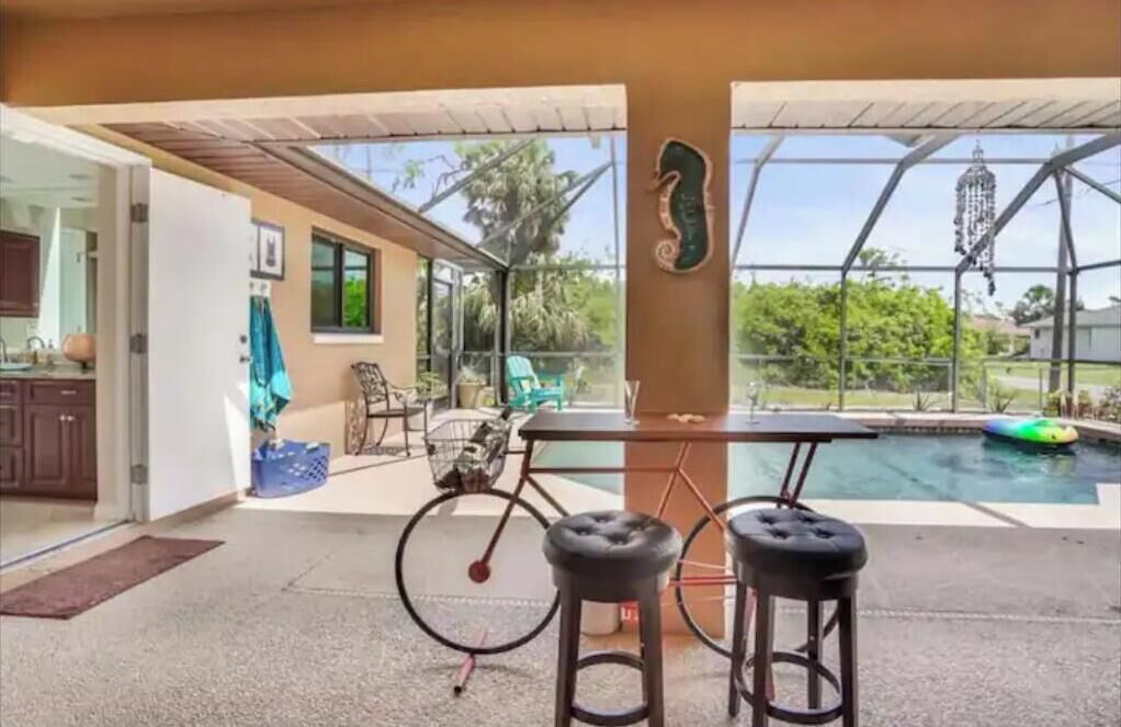 An outdoor patio area with a pool, a bicycle, and two bar stools.