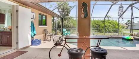 An outdoor patio area with a pool, a bicycle, and two bar stools.
