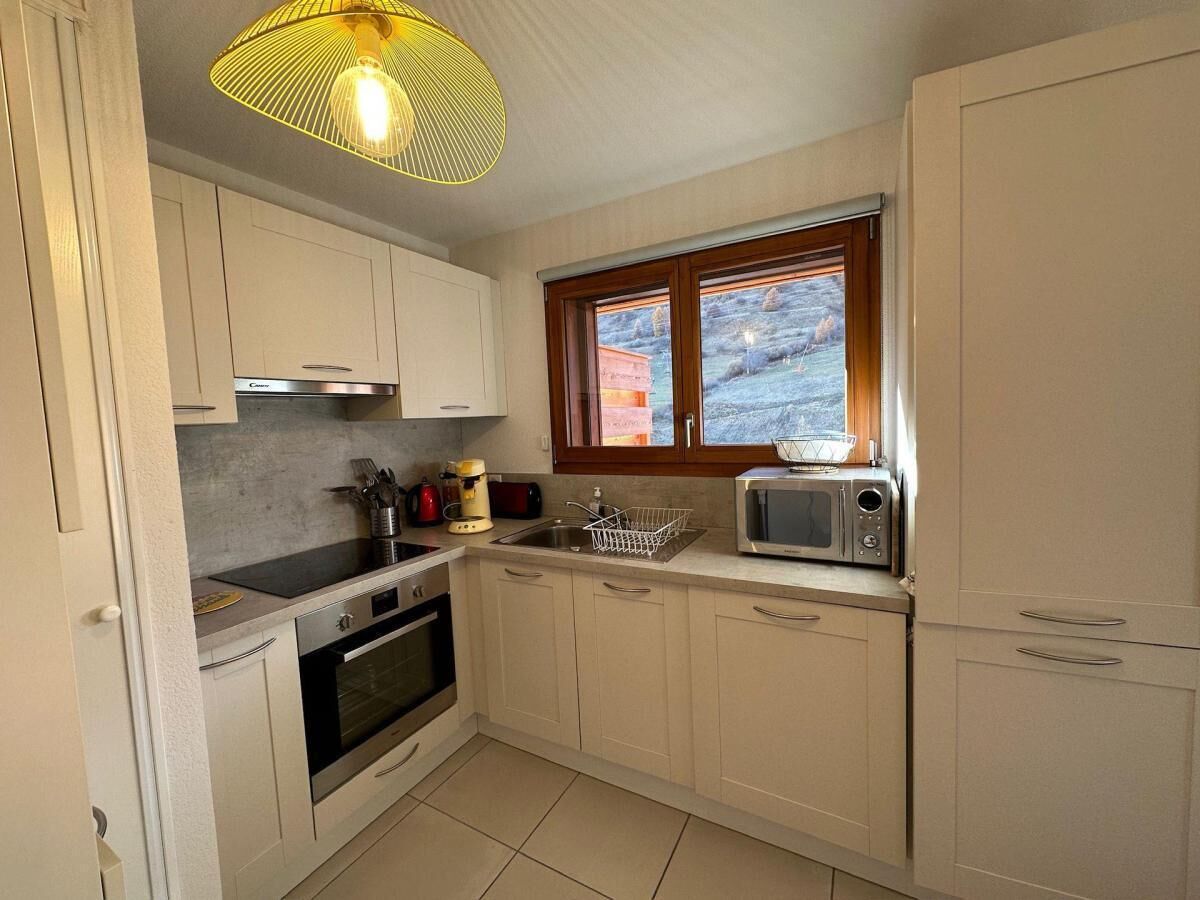 A compact kitchen with white cabinets, a microwave, a stove, and a sink.
