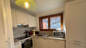 Une cuisine de taille réduite avec des meubles blancs, un four à micro-ondes, une cuisinière et un évier.