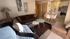 Un salon comprenant un canapé, une table basse et un coin repas avec des chaises.