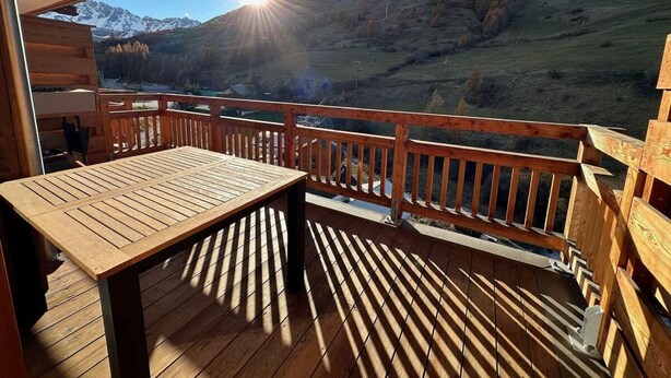 Une terrasse en bois avec une table et des bancs, offrant une vue sur un paysage montagneux.