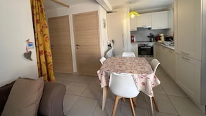 Un espace de vie compact comprenant un coin repas, une kitchenette et un canapé.