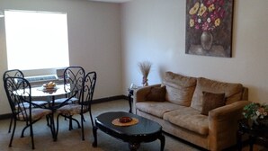 A living room with a beige sofa, a round coffee table, and a dining table with chairs. - Fairway Inn Florence (Florence)