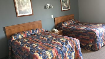 Una habitación con dos camas, cada una con colcha de estampado floral, cabeceros de madera y una mesita de noche con teléfono.