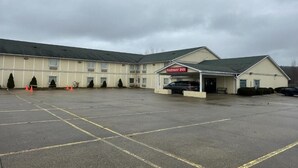 A motel with a large parking lot and a covered entrance. - Fairway Inn Florence (Florence)
