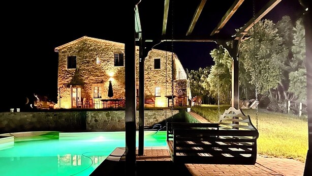 Ein Steinhaus mit Pool und Sitzbereich im Freien bei Nacht.