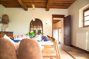 Enjoy meals in this charming dining area with a long table, exposed beams, and a large arched window.