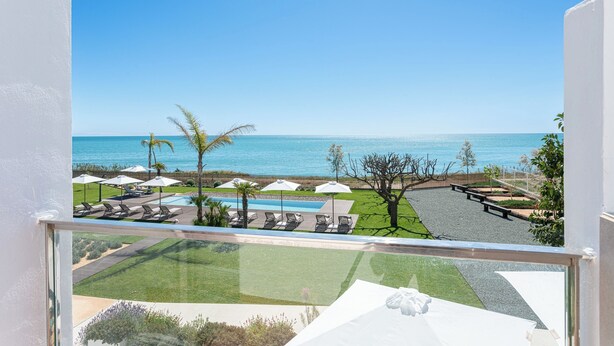 A view of a resort with a pool, lounge chairs, and a beach.