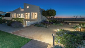 A modern house with a large driveway, a well-maintained garden, and a view of the sea.
