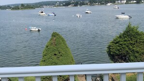 A view of a lake with several boats, a well-maintained lawn, and a white railing.