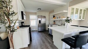 A modern kitchen with white cabinetry, stainless steel appliances, and a central island with seating.