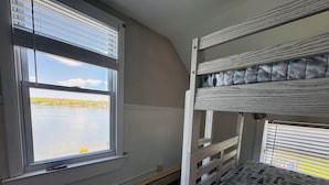A bunk bed room with a window overlooking a body of water.