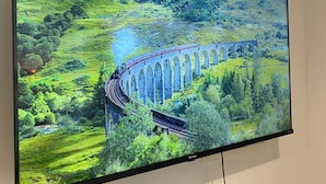 Un televisor muestra un paisaje pintoresco con un tren cruzando un puente.