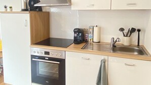 Cocina compacta con estufa, horno, pileta y una pequeña mesada.