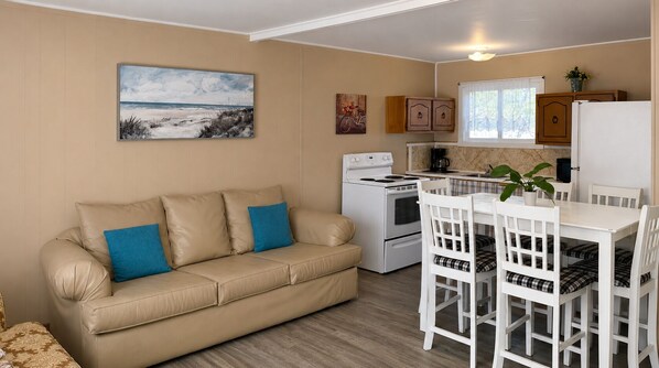 A kitchenette with a stove, a coffee maker, and a refrigerator.