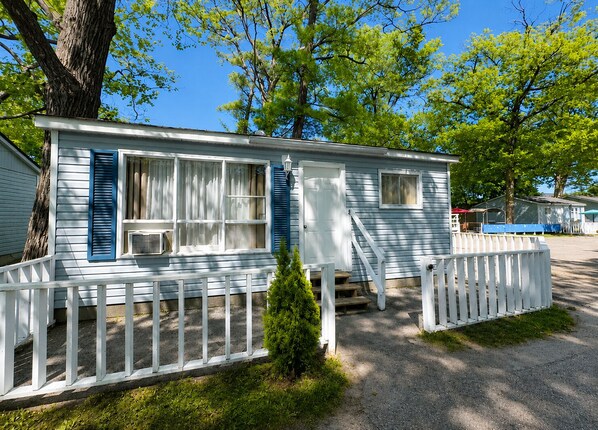 Einbungalow mit Veranda, kleinem Vorgarten und blauem Himmel.